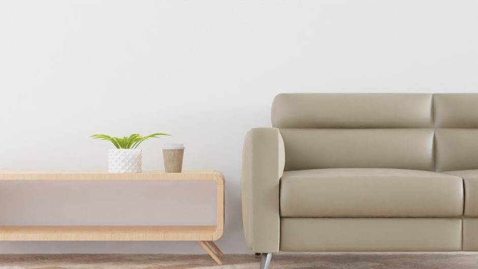 Modern living room with a beige sofa, plant, and coffee cup on a stylish wooden table.